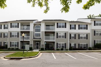 Apartment building with a parking lot in front.